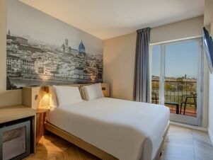 Hotel room at B&B Hotel Firenze Centro with a white bed, large black and white cityscape wall art, balcony, and mounted TV