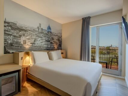 Hotel room at B&B Hotel Firenze Centro with a white bed, large black and white cityscape wall art, balcony, and mounted TV