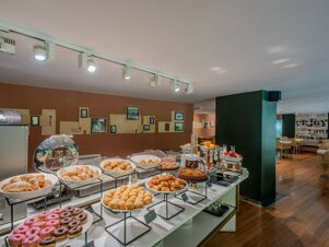 Buffet table with assorted pastries, donuts, pies, fruits, and beverages in the breakfast area of B&B Hotel Firenze Centro