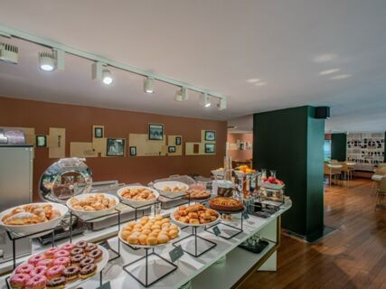 Buffet table with assorted pastries, donuts, pies, fruits, and beverages in the breakfast area of B&B Hotel Firenze Centro