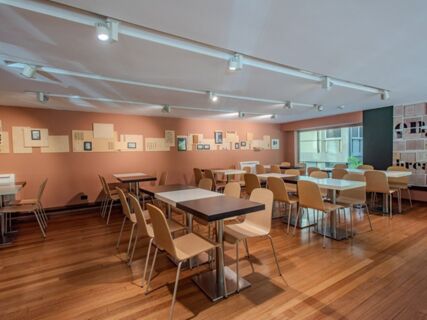 Dining area with wooden chairs and tables on wooden flooring under white ceiling lights at B&B Hotel Firenze Centro