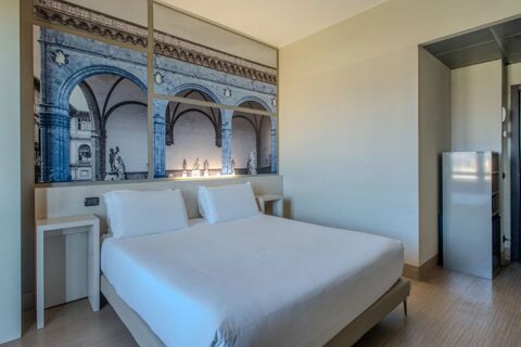 Bedroom in B&B Hotel Firenze Nuovo Palazzo di Giustizia with a double bed, white linens, bedside tables, and artwork of arches on the wall
