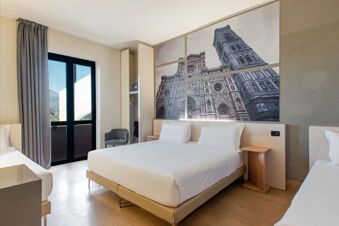 Room interior at B&B Hotel Firenze Nuovo Palazzo di Giustizia featuring two beds, wooden floors, wardrobe, chair, and large window with curtain