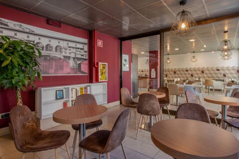 Interior seating area at B&B Hotel Firenze Nuovo Palazzo di Giustizia with round tables, brown chairs, bookshelf, and wall art of a bridge