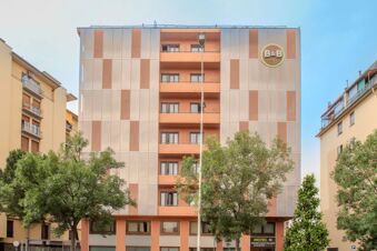 Facade of B&B Hotel Firenze Nuovo Palazzo di Giustizia building with balconies, large windows, trees in front, and streetlamp visible