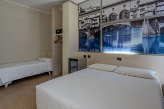 Room at B&B Hotel Firenze Nuovo Palazzo di Giustizia with two twin beds, simple wardrobe with safe, minibar, and wall art of a bridge and river