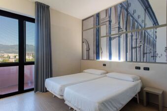 Two single beds with white linens and pillows in a room with a large mural and window at B&B Hotel Firenze Nuovo Palazzo di Giustizia