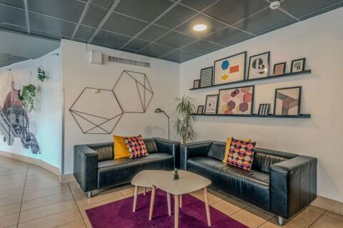 Two black leather sofas with colorful pillows surround a small table on a purple rug against decorated walls at B&B Hotel Firenze Nuovo Palazzo di Giustizia