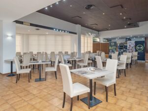 Dining area with white chairs and tables set with placemats and silverware at B&B Hotel Calenzano First