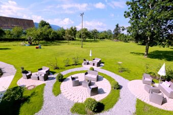 Gro&szlig;er Gartenbereich mit Sitzgruppen und Sonnenschirmen auf gepflasterten Kreisen im Au&szlig;enbereich von Hotel-Restaurant-Cafe Friedenseiche.