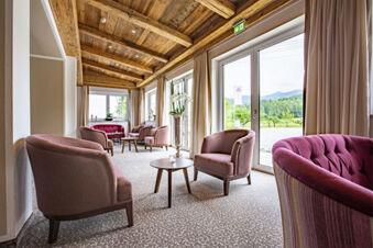 Gem&uuml;tlicher Sitzbereich mit rosa Polstersesseln, Holzbalkendecke und gro&szlig;en Fenstern im Hotel-Restaurant-Cafe Friedenseiche.