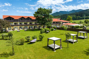 Gro&szlig;e gr&uuml;ne Gartenanlage mit Liegen, H&auml;ngematten und gro&szlig;z&uuml;gigen Sitzbereichen vor dem Hotel-Restaurant-Cafe Friedenseiche, umgeben von Bergen.