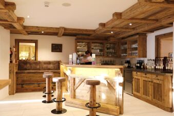 Gem&uuml;tliche Bar mit Holztheke und Hockern im Hotel-Restaurant-Cafe Friedenseiche, eine Mitarbeiterin serviert Getr&auml;nke.