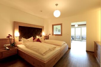 Helles und gem&uuml;tliches Schlafzimmer mit Doppelbett und Balkon im Hotel-Restaurant-Cafe Friedenseiche, elegant mit Holzm&ouml;beln gestaltet.