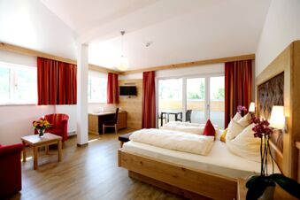 Helles und gem&uuml;tliches Hotelzimmer mit Holzm&ouml;beln und roter Dekoration im Hotel-Restaurant-Cafe Friedenseiche mit Balkon und Aussicht.