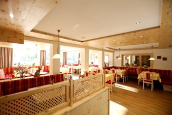 Helles Restaurant mit roten Sitzb&auml;nken und Holzelementen im Hotel-Restaurant-Cafe Friedenseiche, gem&uuml;tliche Atmosph&auml;re mit gedeckten Tischen.