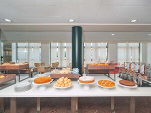 A breakfast buffet with various types of bread, pastries, cakes, and chairs in a dining area at B&B HotelPark Hotel Mondov&igrave;