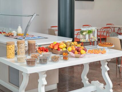 Buffet table with fresh fruits, cereals, nuts, juice dispensers, and a cake in the dining area of B&B HotelPark Hotel Mondov&igrave;
