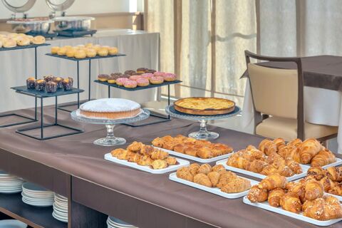 Buffet table with assorted donuts, powdered cake, tarts, croissants, and pastries displayed at B&B HotelPark Hotel Mondov&igrave;
