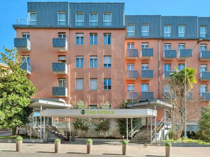 B&B HotelPark Hotel Mondov&igrave; building facade with multiple windows, small balconies, trees, and two staircases at entrance