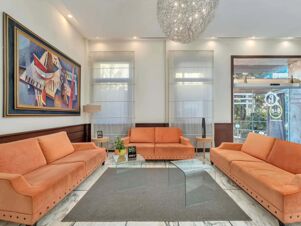 Orange couches surround a gray carpet and glass table in a lobby with modern artwork and lighting at B&B HotelPark Hotel Mondov&igrave;
