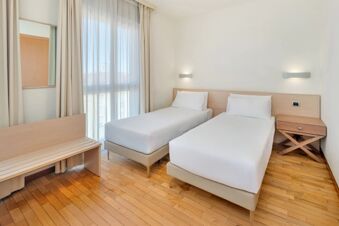 Two single beds with white linens and wooden headboards are placed side by side in a room at B&B HotelPark Hotel Mondov&igrave;