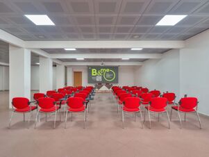 Conference room with rows of red chairs facing a projector screen in a modern meeting space at B&B HotelPark Hotel Mondov&igrave;