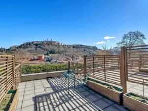Outdoor tiled balcony with metal chairs and table, wooden fencing, and a view of a hillside town at B&B HotelPark Hotel Mondov&igrave;