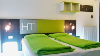 Hotel Garn&igrave; Toreselaのモダンなダブルルームには、グリーンのベッドリネンとミニマルな装飾が施され、フレンドリーな雰囲気に包まれています。