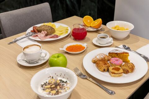 Breakfast table at B&B Hotel Chioggia Airone with assorted pastries, coffee, juice, cold cuts, cheese, fruit, and cereal bowls