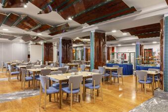 Dining area with multiple wooden tables, gray chairs, wooden pillars, and ceiling panels at B&B Hotel Chioggia Airone