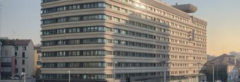 Large multi-story building with horizontal window bands in an urban area during sunset identified as NH Collection Milano Porta Nuova
