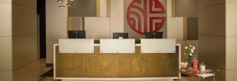 Reception desk with three computer monitors and a decorative gold panel at NH Collection Milano Porta Nuova hotel lobby area