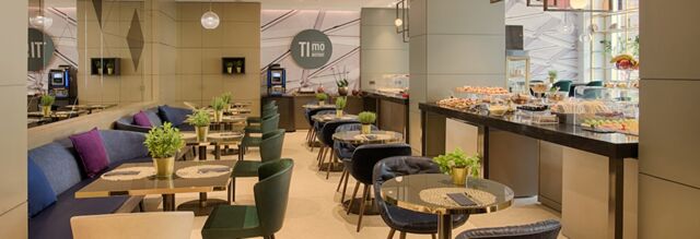 Dining area with tables, chairs, buffet counters with pastries, and plants at NH Collection Milano Porta Nuova