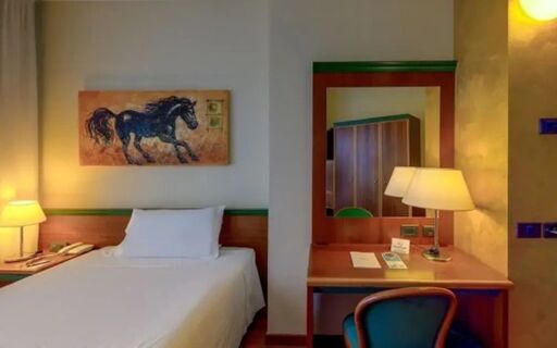 Single bed with white linens and a painting of a horse above it in a room at Hotel Raffaello with a desk and lamp nearby