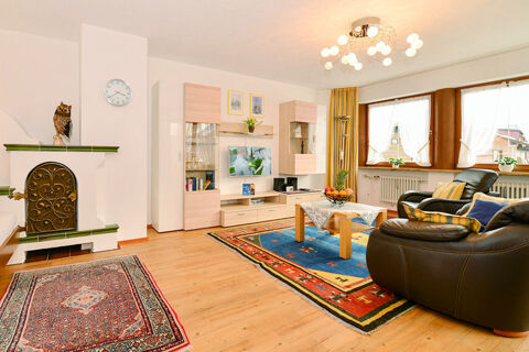 Living room with wooden floor, colorful rugs, leather armchairs, modern cabinet, TV, and owl decoration at Ferienwohnungen W&ouml;rz
