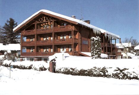 Das G&auml;stehaus zur F&auml;rbe Ferien-Appartements zeigt eine schneebedeckte Holzfassade mit Balkonen und Eiszapfen im Winter.