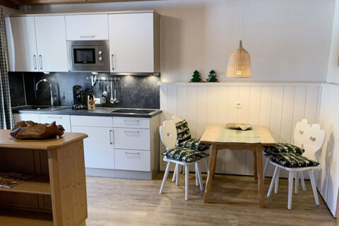 A modern kitchen and dining area with white cabinets, wooden table and chairs with green cushions at Landhaus Berktold
