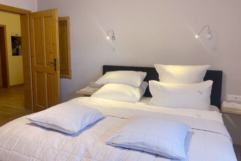 Double bed with white pillows and bedding against a wall with mounted reading lights inside a room at Landhaus Berktold