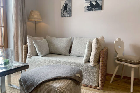 Living room with a cozy cream sofa, several pillows, a wooden side chair with cushion, and a floor lamp at Landhaus Berktold