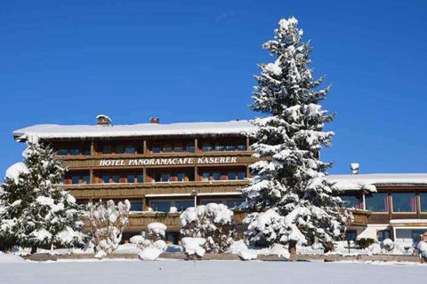 Das Panorama-Hotel Kaserer zeigt sich im Winter mit schneebedeckten B&auml;umen und einem klaren blauen Himmel als charmantes Alpenhotel.