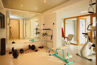 Fitnessraum mit verschiedenen Trainingsger&auml;ten und gro&szlig;en Spiegeln im Panorama-Hotel Kaserer f&uuml;r Sport und Erholung.