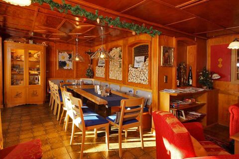 Gem&uuml;tlicher Essbereich im Panorama-Hotel Kaserer mit Holzvert&auml;felung, dekorativem Kaminholz und Sitzgelegenheiten an einem gro&szlig;en Tisch.