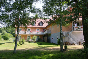 Landgasthof Hotel Hammerm&uuml;hle building with cream walls, red-tiled roof, balcony, trees, and a grassy lawn in front