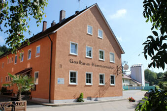 Orange multi-story building with white-trimmed windows and black lettering reading Gasthaus Hammerm&uuml;hle at Landgasthof Hotel Hammerm&uuml;hle