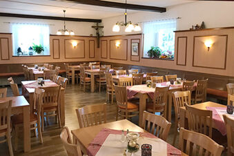 Dining area of Landgasthof Hotel Hammerm&uuml;hle with wooden chairs and tables covered with pink and white tablecloths and wall decorations