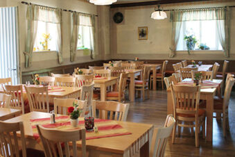 Dining area with wooden tables and chairs, tablecloths, flowers, and curtains at Landgasthof Hotel Hammerm&uuml;hle