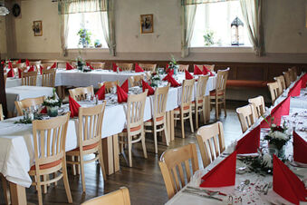 Dining room setup with wooden chairs, white tablecloths, red napkins, and flowers at Landgasthof Hotel Hammerm&uuml;hle