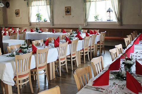 Dining room setup with wooden chairs, white tablecloths, red napkins, and flowers at Landgasthof Hotel Hammerm&uuml;hle