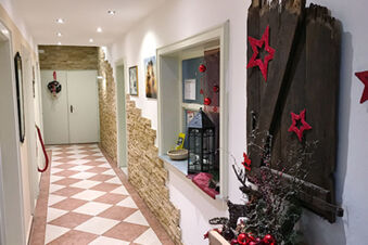 Hallway in Landgasthof Hotel Hammerm&uuml;hle with white and brown tiled floor, stone wall accents, and Christmas decorations visible